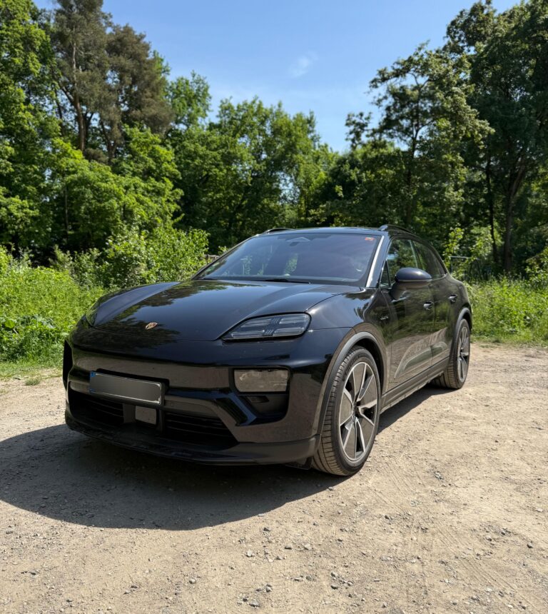 Porsche Macan in Schwarz, Frontansicht schräg links, vor Bäumen