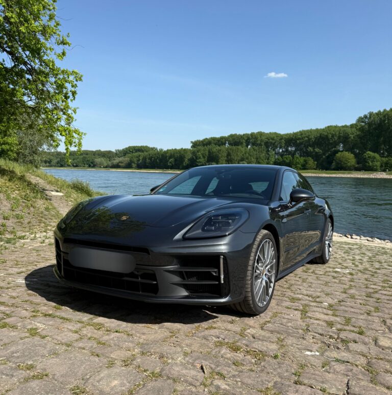 Porsche Panamera in Dunkelgrau, Frontansicht schräg links, an einem See