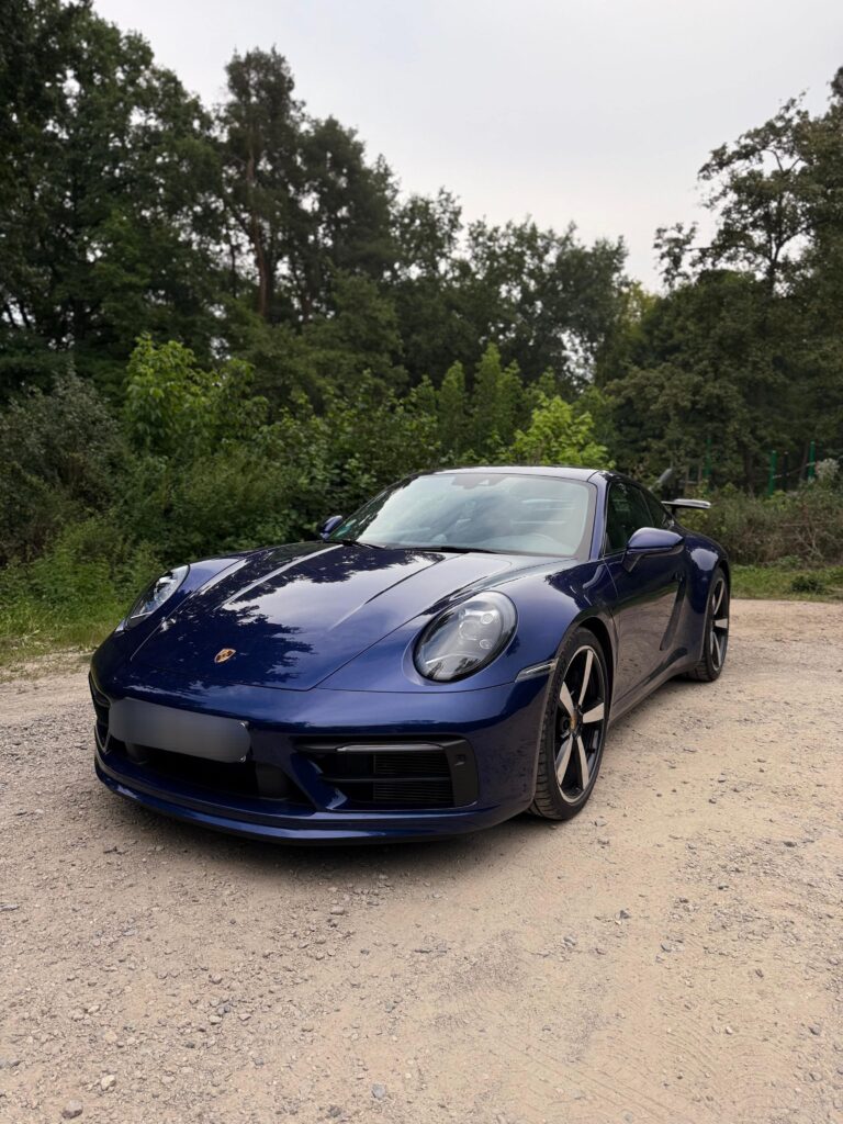 Porsche 911 in Dunkelblau, Seitenansicht links, auf einer Wiese