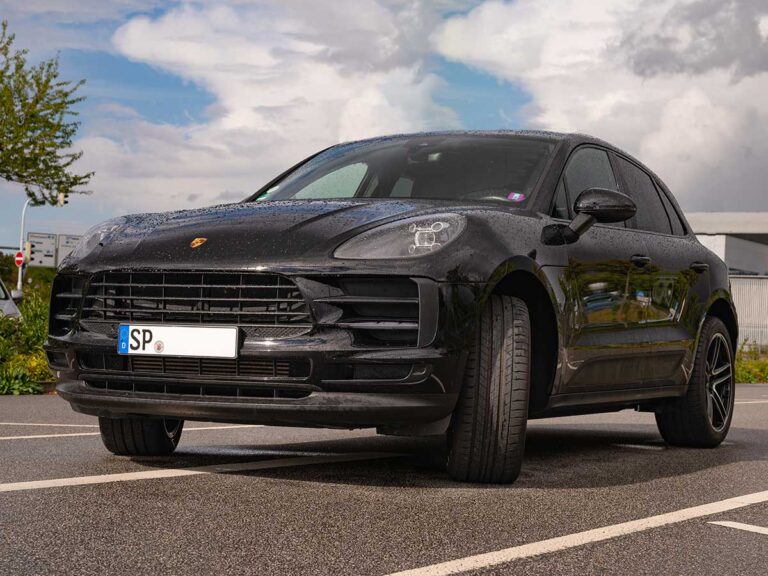 Porsche Macan in Schwarz, Frontansicht schräg links, auf einer Straße